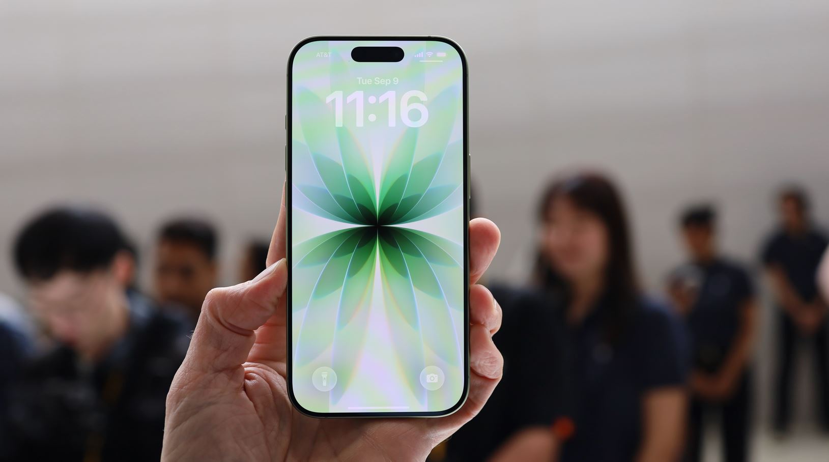 iPhone 17 с зелёной заставкой в руке