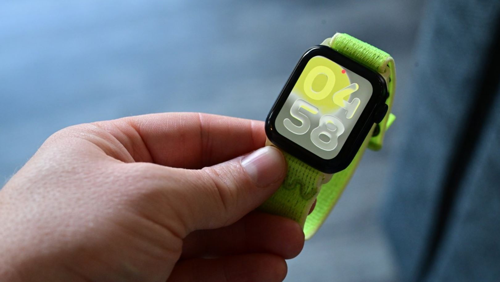 Компактные Apple Watch SE 3 с зелёным ремешком в руке