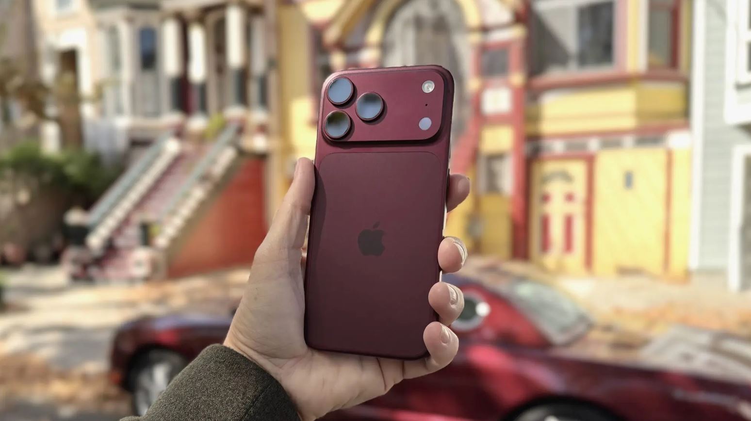 Бордовый iPhone 18 Pro в руке на городской улице