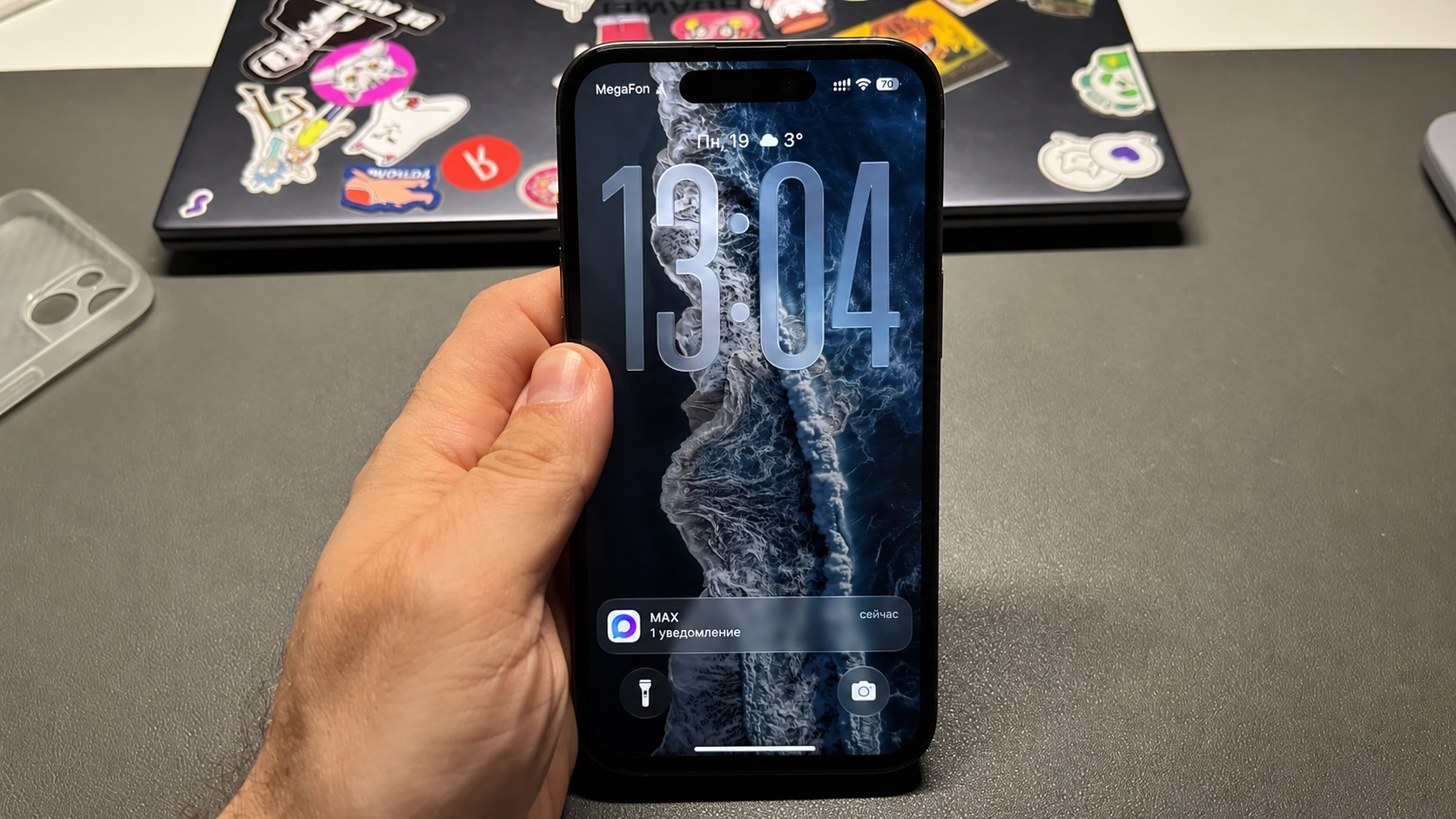 iPhone 15 Plus с экраном блокировки в руке