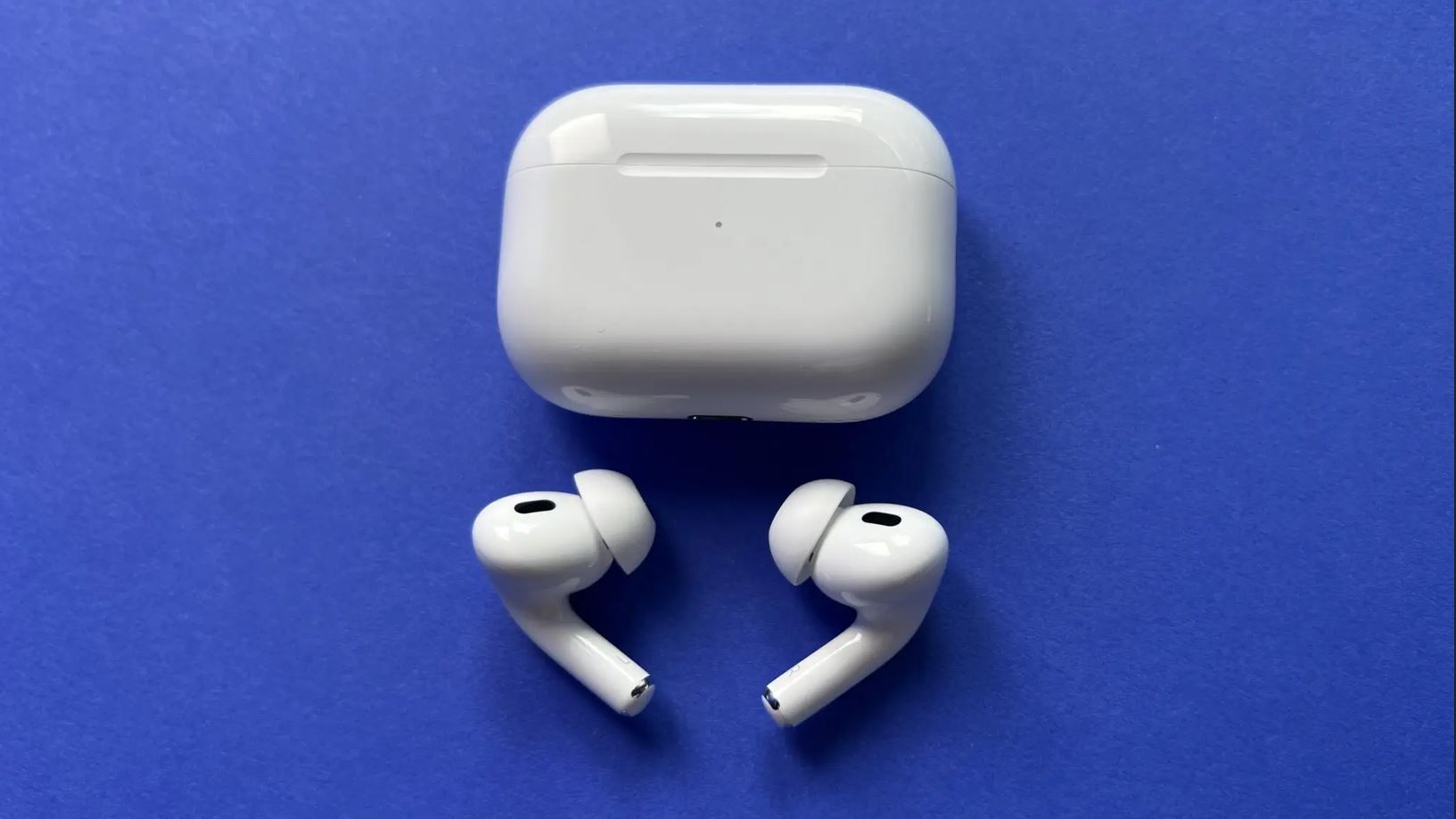 Два наушника AirPods перед закрытым зарядным футляром