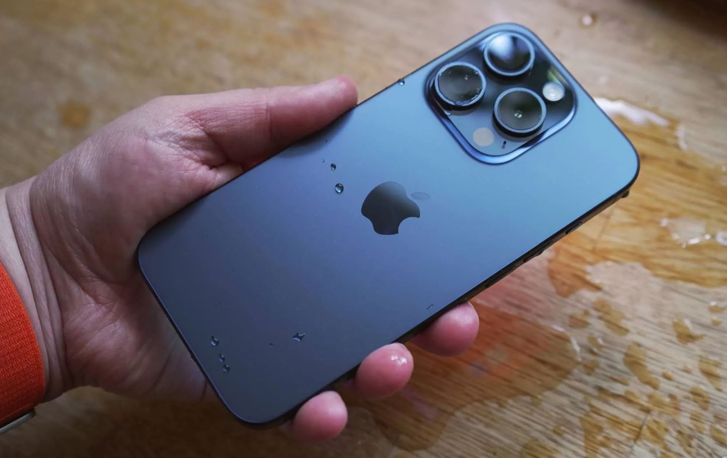 Синий iPhone 15 Pro со следами износа в руке