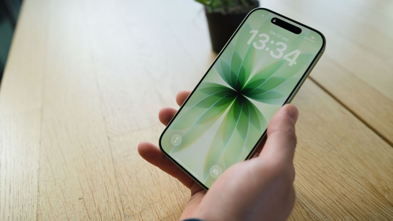 Экран iPhone 17 в руке над столом